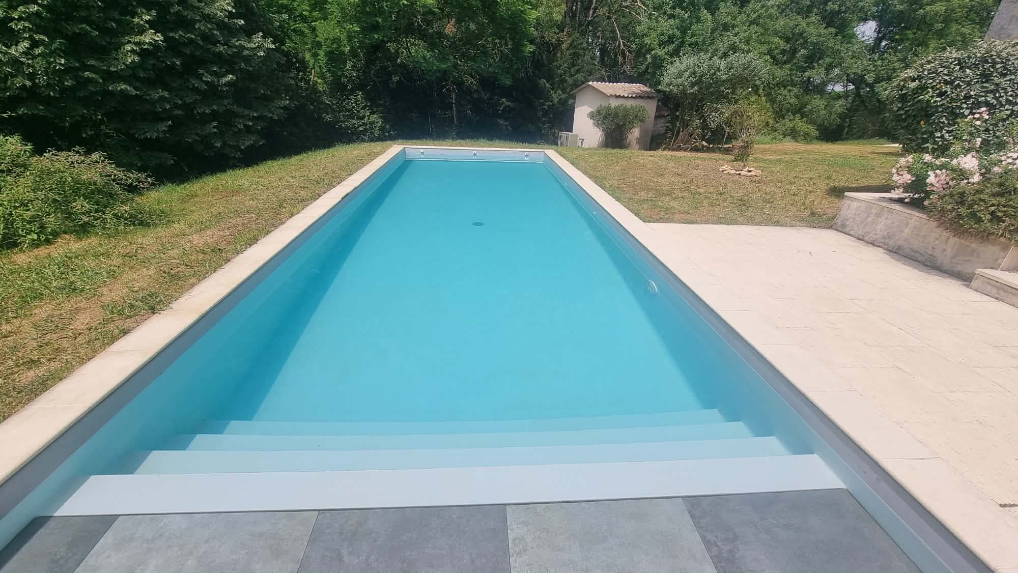 La grande piscine chauffée entourée de verdure